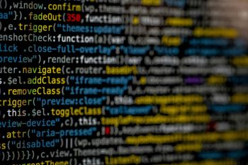 Gros plan flou sur du code JavaScript à l'écran, illustrant la densité du code bloated qui alourdit un site web.